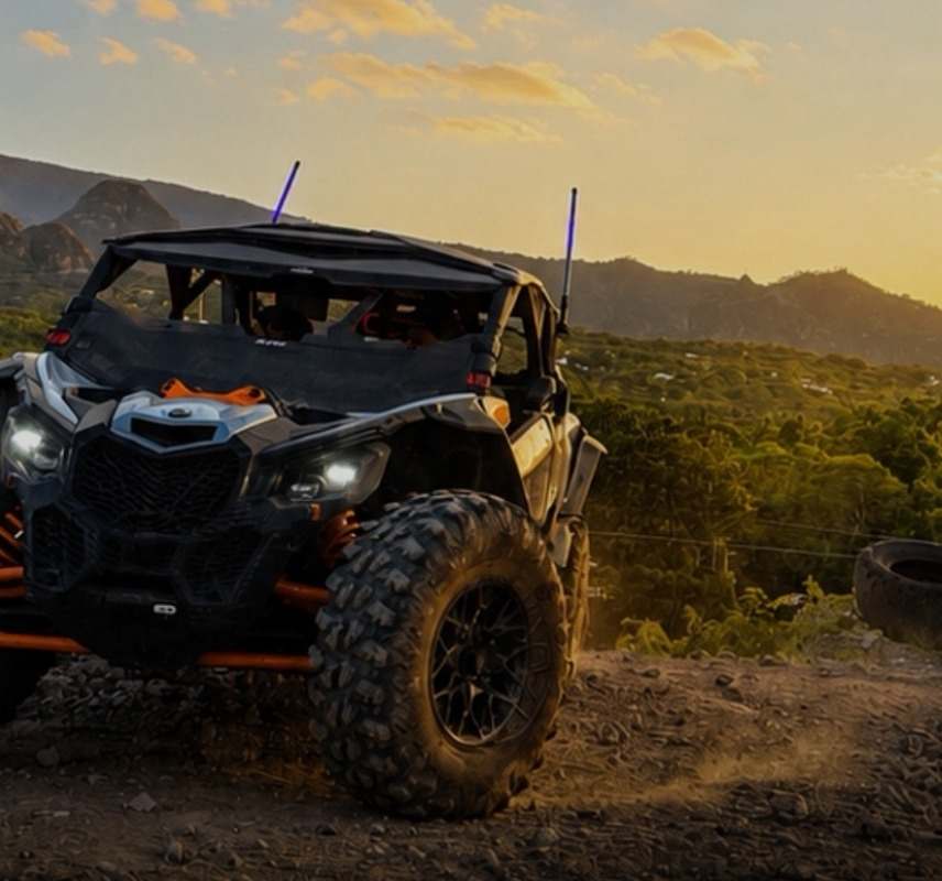 Maverick X3 con las luces encendidas en un camino de tierra, con los cerros de Tepoztlán bajo luz dorada.