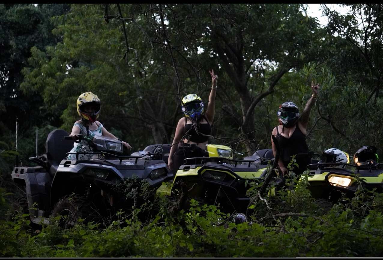 Tres cuatrimotos con sus pilotos con casco entre los árboles.